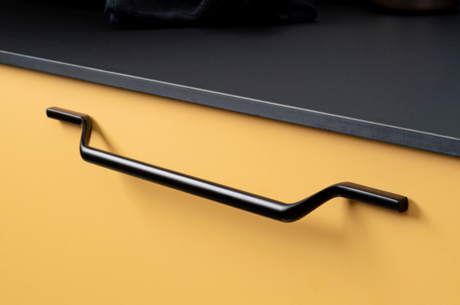 poignee de meuble noir sur un meuble jaune